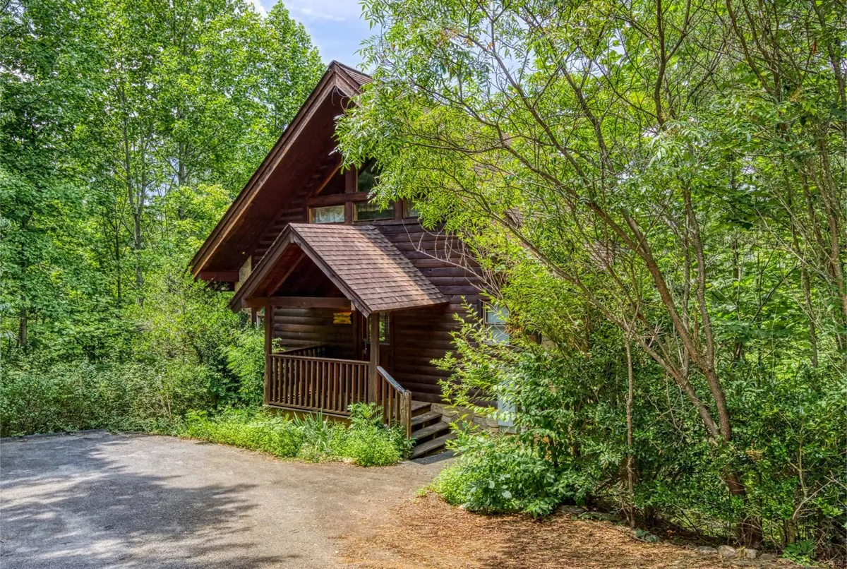 This image captures a charming log cabin with a wooden porch nestled among lush greenery. The porch offers a cozy seating area perfect for relaxing while surrounded by nature, suggesting the tranquil seclusion described in the section. The natural setting and the inviting porch directly evoke the idea of enjoying peaceful mornings or romantic evenings together.