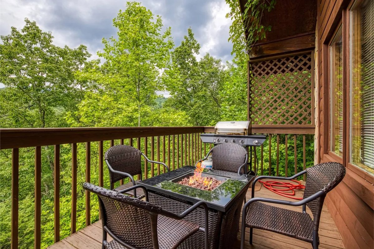 An outdoor seating area featuring a fire pit, grill, and comfortable chairs, surrounded by trees. The setting is ideal for gathering with friends and family, sharing stories, or simply enjoying the mountain air after a day of activity.