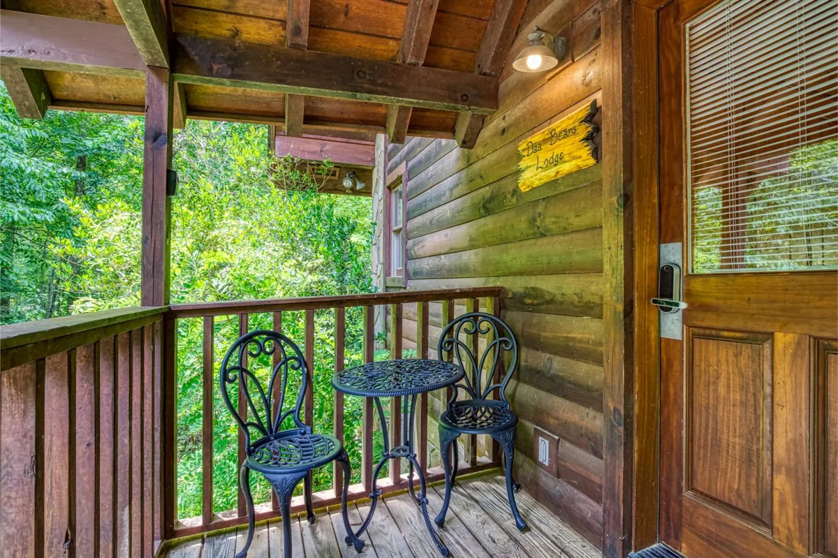 An outdoor deck featuring a small round table and two ornate chairs, set against a lush green backdrop. The scene is inviting for morning coffee or evening conversations, suggesting privacy and a close connection to nature.