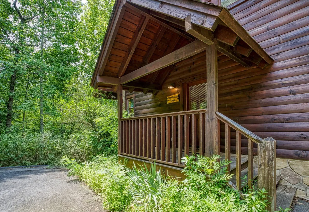 A wooden porch overlooking lush greenery and a stone pathway, framed by natural surroundings. The space exudes tranquility, making it an ideal spot for unwinding or social gatherings after active leisure pursuits.